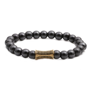 Bracciale in ematite nera lucida con un cilindro dorato decorato con cristalli neri