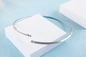 Close-up of polished silver titanium steel choker with pin clasp on geometric base