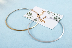 Flat lay of minimalist gold and silver polished metal choker necklaces with clasp detail