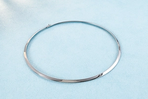 Flat silver choker collar with invisible clasp on light blue textured background