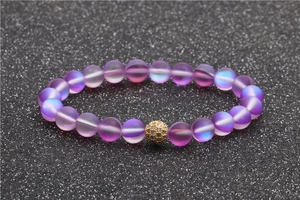 Détail de perles de pierre de lune givrées avec boule de cristal dorée sur fond noir