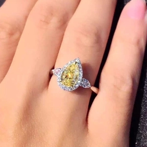 Minimalist pear-shaped yellow zircon halo ring with side stones worn on finger