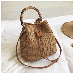 Detail of straw bucket bag with bamboo handle and leather drawstring closure