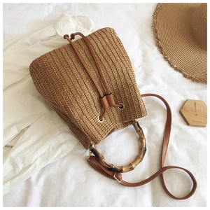 Detail of hand-woven straw bucket bag featuring vintage bamboo handle and leather drawstring