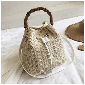 Detail of straw bucket bag with bamboo handle, white PU drawstring and woven texture
