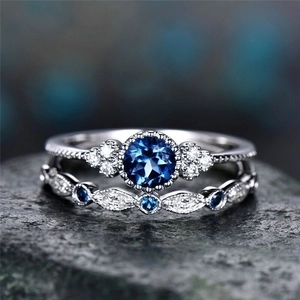 Macro view of blue zircon engagement ring set with silver band on grey stone