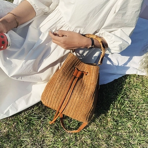 Straw bucket bag with bamboo handles and adjustable shoulder strap for summer beach fashion