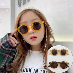 Close-up of children's round leopard print sunglasses worn by a young model outdoors