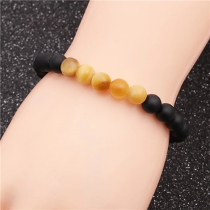 Matte black and yellow tiger eye beaded bracelet displayed on a hand model