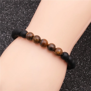Detail of matte black beads and brown tiger eye stone bracelet on a wrist model