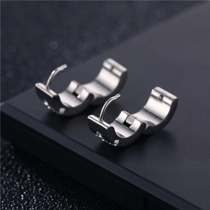 Macro shot of polished steel huggie earrings with inlaid square cubic zirconia stone