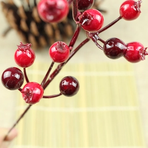 Artificial red pomegranate berries for Christmas decoration with rustic pine cone background