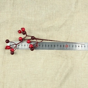 Detail view of 26cm artificial red berry stems with size scale on rustic burlap background