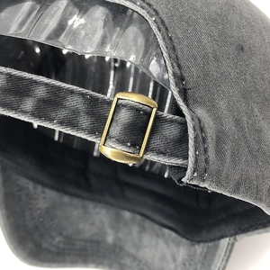Detail of stone-washed cotton baseball cap with adjustable antique bronze metal buckle