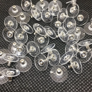 Macro shot of bulk clear plastic earring backs with silver metal discs on black base