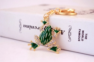 Macro shot of green enamel frog keychain with sparkling crystals on a book edge