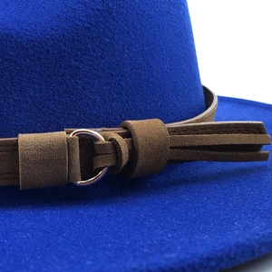 Close-up detail of the brown decorative belt and silver buckle on a royal blue fedora hat