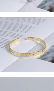 Detail of gold open bangle showing hammered texture and S925 hallmark on inner band