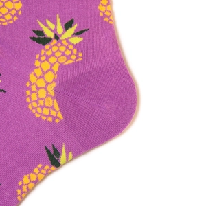 Close-up of purple cotton socks featuring yellow pineapple patterns and knit texture