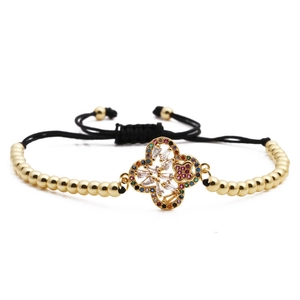 Macro shot of gold beaded bracelet with colorful zircon pavé clover pendant details