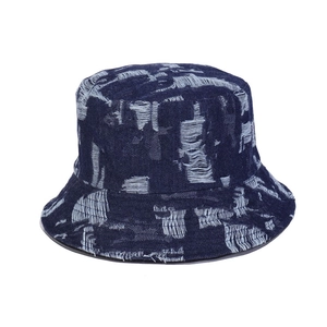 Detail of distressed denim bucket hat featuring vintage ripped holes and frayed texture