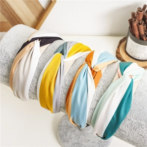 Detail of four colorful striped knot headbands displayed on a grey stand