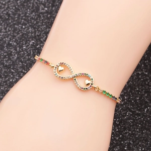 Macro detail of gold infinity heart bracelet with multi-color zircon stones on black background