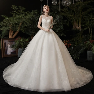 Elegant white ball gown wedding dress with lace embroidery and sequins in a forest setting