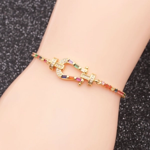 Gold-plated horseshoe link bracelet with rainbow cubic zirconia on a model's wrist