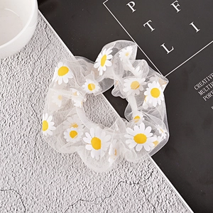 Detail shot of white mesh scrunchie with yellow daisy floral prints on grey background