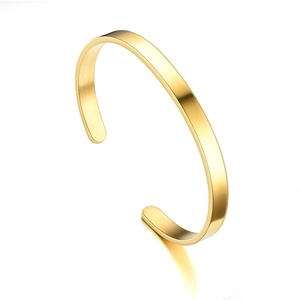 Detailed macro view of a polished golden stainless steel C-shaped open cuff bracelet
