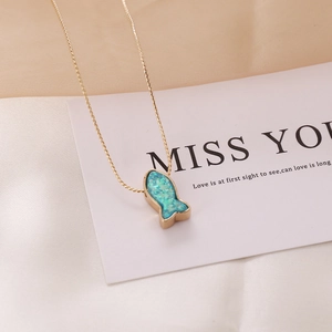 Golden necklace with blue mermaid fish pendant on silk background, elegant jewelry for women