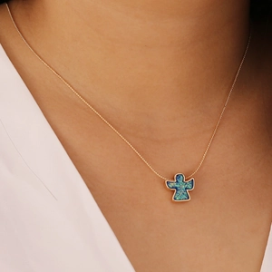 Close-up of a gold necklace featuring a blue opal angel pendant worn by a model