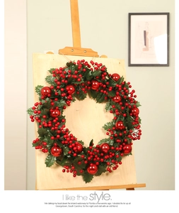 Detail of red berries and green leaves on a Christmas wreath displayed on a wooden stand