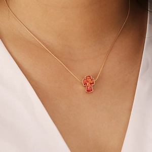 Golden delicate chain necklace featuring a vintage red cross pendant on model neck