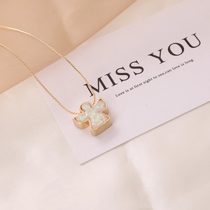 Macro view of gold angel pendant with shimmering white inlay on a delicate chain