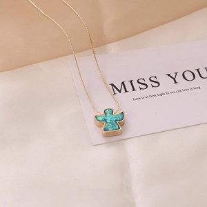 Close-up of a gold angel pendant necklace with blue opal inlay on white silk fabric
