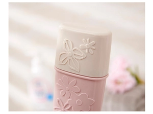 Close-up of pink and beige portable toothbrush case featuring floral relief texture