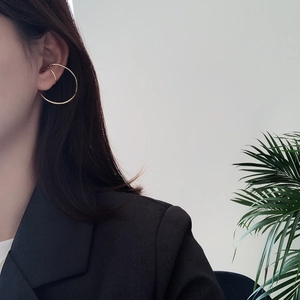 Close-up of elegant gold horseshoe ear cuff and hoop earring set on female model