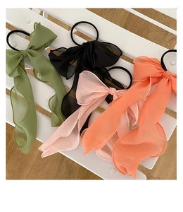 Detailed flat lay of four large chiffon bow hair ties in green, black, pink, and orange
