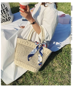 Detailed texture of hollow woven straw bag with decorative floral silk scarf handle