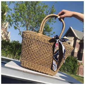 Close-up of hand-woven straw tote bag with nautical pattern silk scarf handle detail