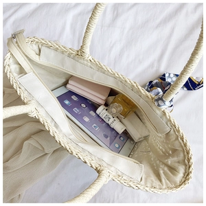 Detail view of woven straw tote bag interior with zipper and decorative scarf