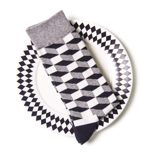 Detail of a geometric black and white patterned cotton sock on a creative checkered plate