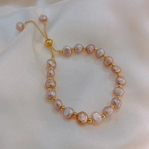 Detail of lavender freshwater pearls and gold beads on elegant white silk background