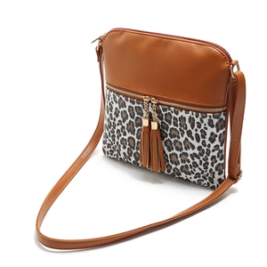 Detail shot of leopard print patchwork and double tassel charms on brown crossbody bag