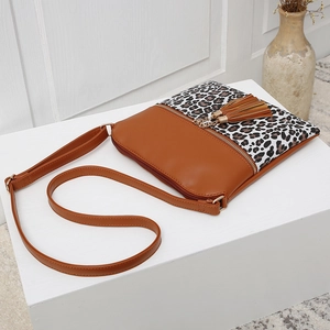 Detail of crossbody bag featuring leopard print, brown faux leather and double tassels
