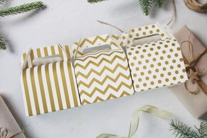Detail view of gold and white patterned paper cake boxes with stripe and dot designs