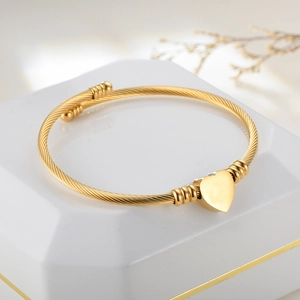 Macro detail of gold-plated twisted cable bracelet with a polished heart pendant