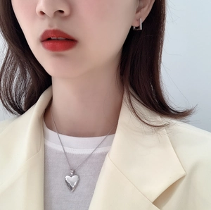 Detail of 925 sterling silver heart necklace and rectangular hoop earrings on model